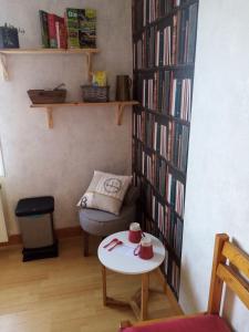 a living room with a table and a book shelf with books at maison aux volets bleus in Quévert