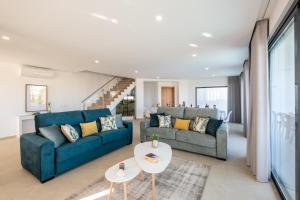 a living room with two blue couches and a table at Villa Charlotte by Algarve Vacation in Armação de Pêra