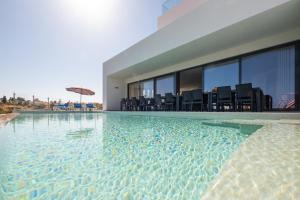 einen Pool mit Stühlen und einem Sonnenschirm in einem Gebäude in der Unterkunft Villa Charlotte by Algarve Vacation in Armação de Pêra