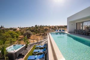 ein Pool mit blauen Stühlen und ein Haus in der Unterkunft Villa Charlotte by Algarve Vacation in Armação de Pêra