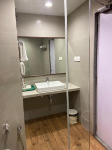 y baño con lavabo y espejo. en Chryso Hotels Pvt Ltd, en Ankleshwar