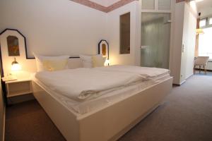 a large white bed in a room with a window at Hotel Zur schönen Aussicht in Grömitz