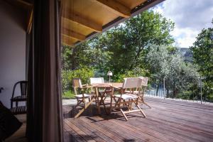 einen Holztisch und Stühle auf einer Holzterrasse in der Unterkunft Quinta dos Carqueijais Gerês in Geres