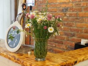 wazon kwiatów na stole obok zegara w obiekcie Zacisze Trzech Gór w Jedlinie-Zdroju