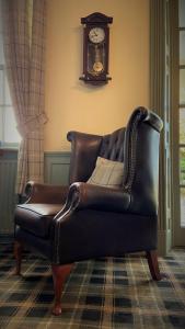 a leather couch in a living room with a clock at Hickman Hill Hotel in Gainsborough