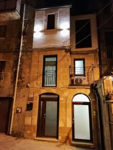 a building with two doors and a balcony at night at La casa in piazzetta in Enna