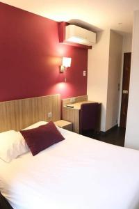 um quarto com uma cama branca e uma parede vermelha em HOTEL DU COMMERCE em La Châtre