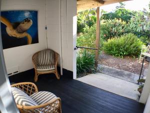 una porta aperta su un portico con sedie e un quadro di High Tide at Emerald a Emerald Beach