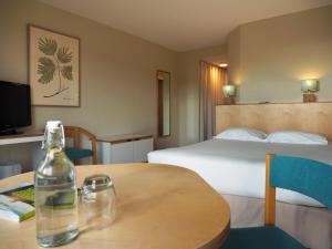 a hotel room with a bed and a bottle on a table at Logis Hôtel du Belvédère in Brest