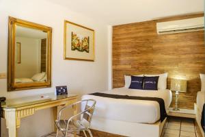 a bedroom with a bed and a desk and a mirror at Capital O Hotel Dos Mares, Cabo San Lucas in Cabo San Lucas