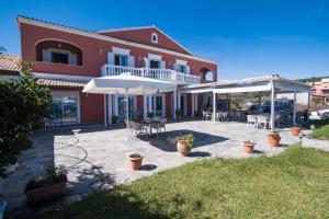una casa con patio attrezzato con tavoli e ombrelloni di Christina Beachfront Rooms By Hotelius a Petrití
