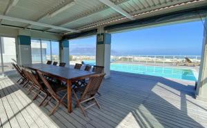a wooden deck with a table and chairs next to a swimming pool at Sea Spray in Bloubergstrand
