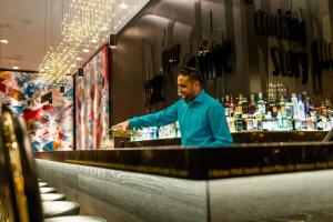 a man standing behind a bar with a bottle of wine at Motel One Frankfurt-Römer in Frankfurt/Main