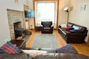 a living room with leather couches and a fireplace at Freeland Cottage in Dunoon