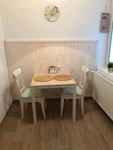 uma mesa e cadeiras num quarto com um relógio na parede em L&R Apartment em Gyor