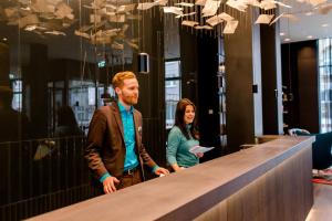 a man and a woman standing at a counter at Motel One Frankfurt-Römer in Frankfurt/Main