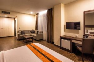 een hotelkamer met een bank en een televisie bij Oria Hotel Jakarta in Jakarta