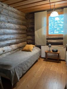Muurame的住宿－Kelotulkku Lodge，一间卧室设有木墙、一张床和一张桌子