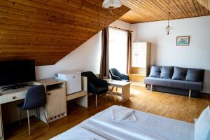 テルキバーニャにあるAranybánya Panzió és Apartmanházのベッド、ソファ、デスクが備わる客室です。