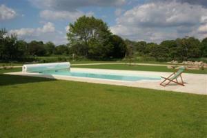 a swimming pool with a chair in the grass at Le clos Saint Aubin in Carnac