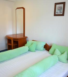 two beds with green pillows in a room with a desk at Hotel Iadolina in Stana de Vale