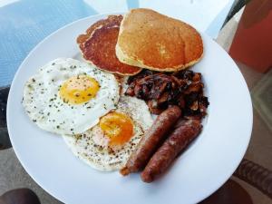 a plate of breakfast food with eggs sausage and pancakes at Mashusha Bed & Breakfast in Gaborone