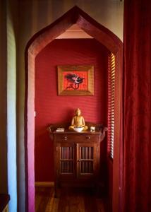 una habitación con una pared roja y una mesa con una estatua en Tomah Retreat - Studio CHILL with fireplace and clawfoot bath en Mount Tomah