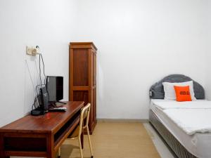 1 dormitorio con escritorio, ordenador y cama en KoolKost Syariah near Universitas Diponegoro Tembalang 2, en Srondolwetan