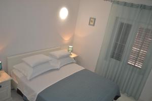 a bedroom with a bed with pillows and a window at Corto Maltese in Brgulje
