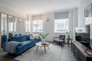 ein Wohnzimmer mit einem blauen Sofa und einem TV in der Unterkunft Kula London - Victoria in London