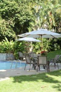 a table and chairs with an umbrella next to a pool at Hotel Santa Amalia in Vassouras