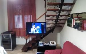 uma sala de estar com televisão e uma escada em espiral em Affitta Camere Monte Grappa em Tempio Pausania