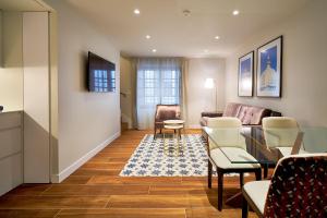 a living room with a couch and a table and chairs at Tandem Torres de Cádiz Suites in Cádiz