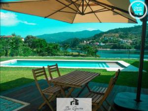Ein Holztisch und Stühle unter einem Sonnenschirm neben einem Pool in der Unterkunft ERMAL HOUSE in Braga