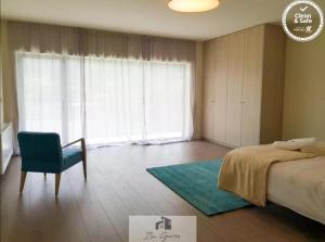 ein Schlafzimmer mit einem Bett und einem Stuhl und einem Fenster in der Unterkunft ERMAL HOUSE in Braga