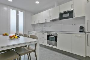 una cocina blanca con una mesa con un bol de fruta. en Stay Together Barcelona Apartments, en Barcelona