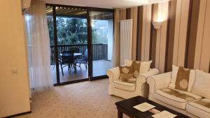 un soggiorno con 2 sedie e un tavolo e un balcone di Apartament 2706 Alpin Resort, etaj 7, Poiana Brașov a Poiana Brasov Altre 37 foto