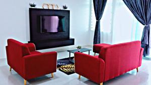 a living room with two red chairs and a tv at MARI Residence in Kuala Terengganu