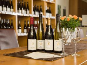Gästehaus & Weingut PETH في Flörsheim-Dalsheim: أربعة زجاجات من النبيذ تجلس على طاولة مع كؤوس للنبيذ