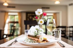 a white plate with a sandwich and a glass of wine at Naturhotel Schloss Kassegg in Sankt Gallen