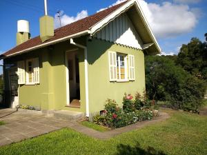 a small green house with flowers in the yard at Cabana Canela in Canela