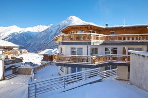 una casa nella neve con montagne sullo sfondo di A Casa Alpendiamond a Sölden