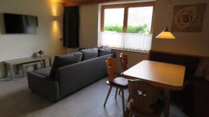una sala de estar con un sofá y una mesa en Braunhof Apartments, en Hainzenberg