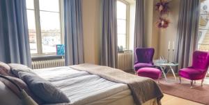 1 dormitorio con 1 cama y 2 sillas moradas en Maritim Hotell & Krog, en Simrishamn