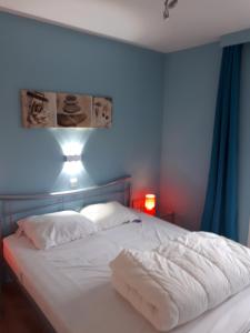 a bedroom with a white bed with a blue wall at Résidence Jersey (app. 201) in Koksijde