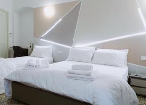 a bedroom with two beds with white sheets and towels at Centro Acquario Family in Genoa