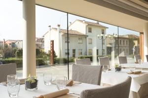 um restaurante com mesas e cadeiras brancas e uma grande janela em Best Western Hotel Continental em Udine