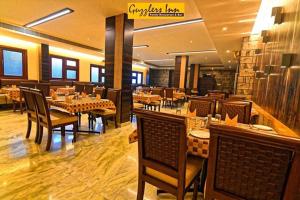 马尼帕尔Hotel Ashlesh Manipal的一间有桌椅的餐厅