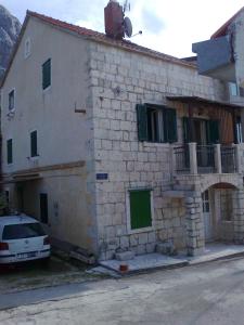 a stone building with a car parked in front of it at Apartman Zora in Drasnice