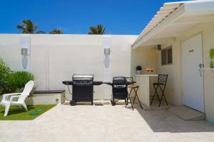 Yoyita Suites Aruba في شاطئ بالم إيغل: فناء به شواية وكراسي أمام جدار أبيض